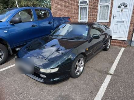 A dark green sports coupe on the forecourt